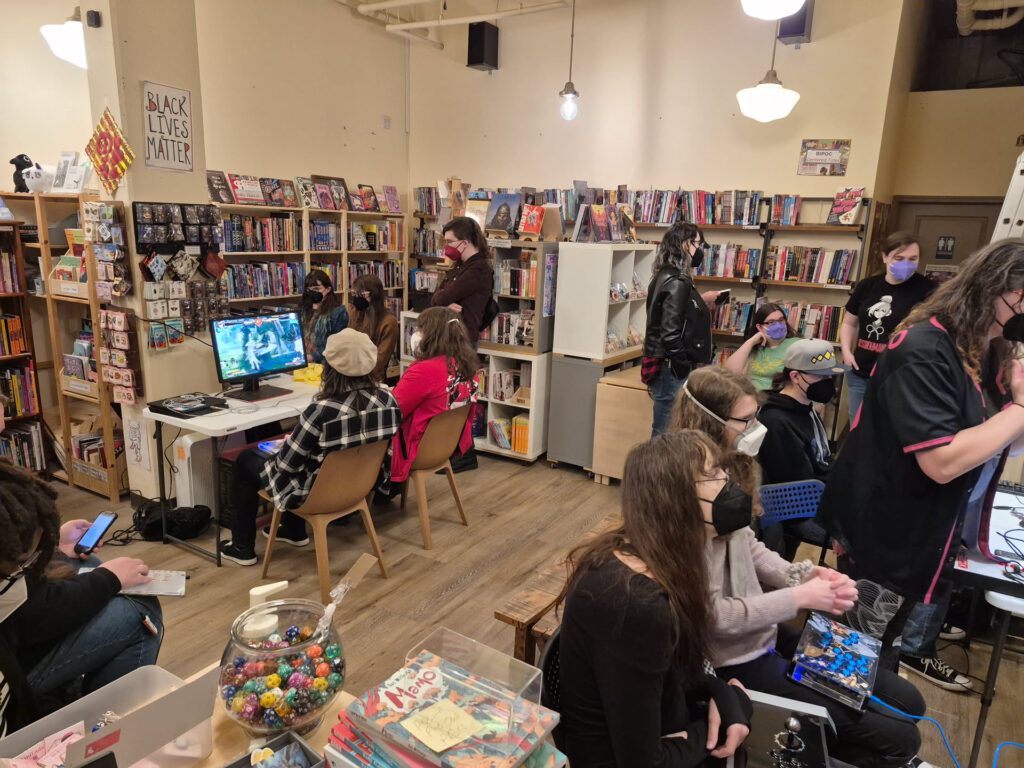 Photo of bookstore with about 10 people playing video games. They are all wearing masks.